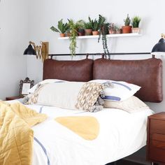 a bed with lots of pillows and plants on the headboard