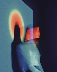 a blurry image of a person standing in front of a wall with an orange circle