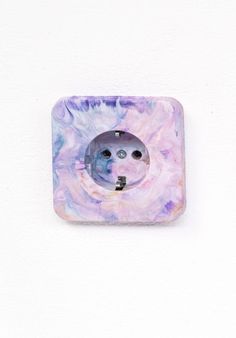 a button that is on the side of a white wall with purple and blue designs