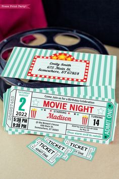 two movie night tickets sitting on top of a table next to a pair of scissors