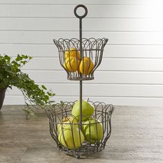 a metal fruit stand with apples and oranges in it