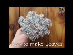 a hand holding a piece of silver wire with the words how to make leaves on it