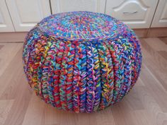 a multicolored knitted poufce sits on the floor