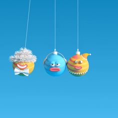 three ornaments hanging from strings in the shape of fish and clown heads on a blue sky background