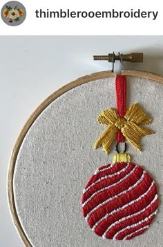 an embroidered ornament hanging from a hoop with a red and white ball on it