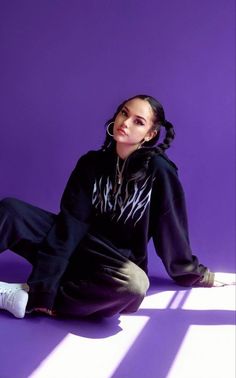 a woman sitting on the ground wearing a black hoodie