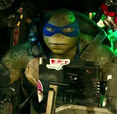 the teenage mutant in teenage mutant is holding an electronic device and looking at the camera