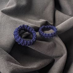 two blue crocheted hair ties on top of a gray fabric material with folds