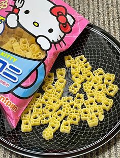 a hello kitty snack bag sitting on top of a black plate next to some cheetos