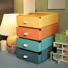 four drawers are stacked on top of each other in front of a lamp and pictures