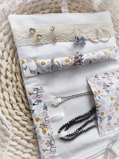 a basket filled with lots of jewelry on top of a white cloth covered table next to a wicker basket