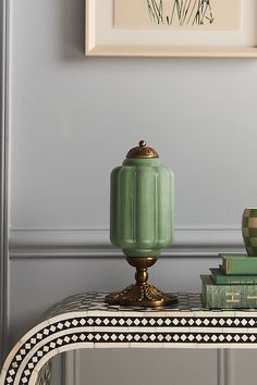 a table with some books on it and a vase sitting on top of the table