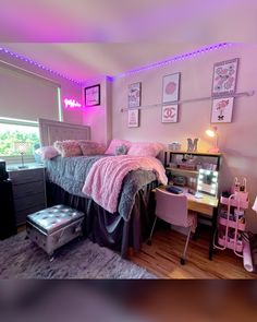 a bedroom with pink lights and pictures on the wall above the bed, along with a desk