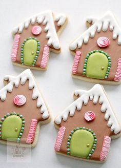 four decorated gingerbread cookies with icing and candy toppings in the shape of a house