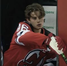 a young man in red jersey holding a hockey stick