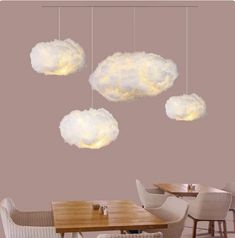 three clouds hanging from the ceiling above a dining room table with four chairs and two tables