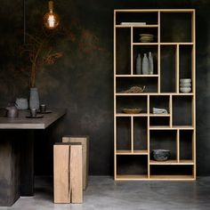 a wooden shelf sitting next to a table with vases and other items on it