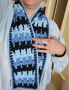 an older woman wearing a crocheted scarf in blue, black and white colors