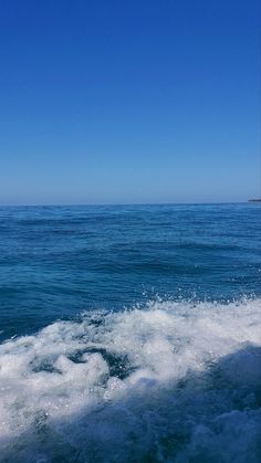 the wake of a boat in the ocean on a sunny day with blue sky and water