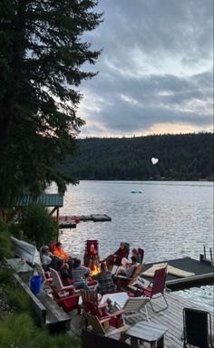 the fire pit is set up on the dock by the water's edge with chairs around it