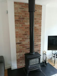 a living room with a brick wall and a wood burning stove in the middle of it