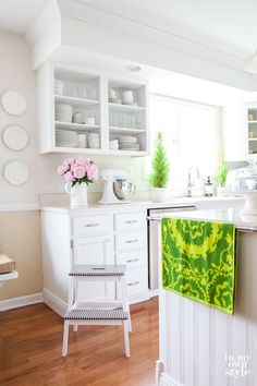 a kitchen with white cabinets and green towels hanging from the rack on the wall above the sink