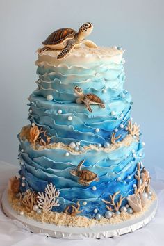 a three tiered cake decorated with sea turtles and seashells