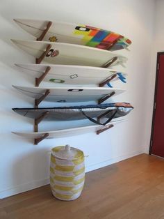 several surfboards are mounted to the wall in a room with wood floors and white walls