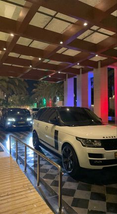 two cars are parked in front of a hotel lobby with checkered tile flooring