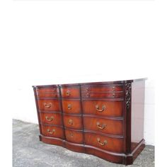 a large wooden dresser sitting on top of a cement floor next to a white wall