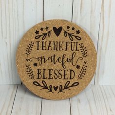 a cork coaster that says, thank grateful and is decorated with leaves on the front