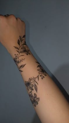 a woman's arm with flowers and leaves tattooed on the side of her arm