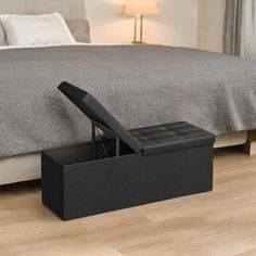 a bed sitting on top of a wooden floor next to a black box with a seat