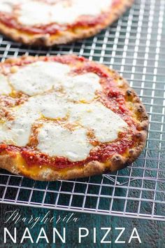 two pizzas sitting on top of a cooling rack next to each other, one topped with cheese