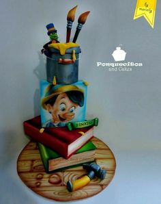 a cake made to look like a cartoon character with books and paintbrushes on it