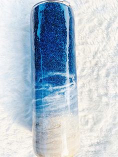 a blue and white vase sitting on top of a snow covered ground next to a wall