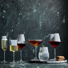 four different types of wine are lined up on a marble counter top with crackers