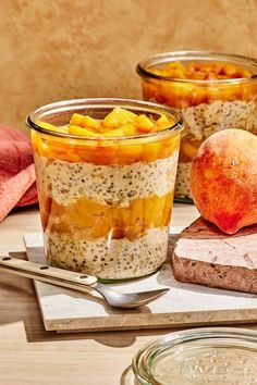 two jars filled with food sitting on top of a wooden cutting board next to bread