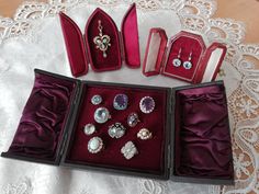 an assortment of jewelry in velvet cases on a lace tablecloth with white doily