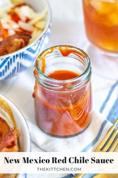 two bowls of chili sauce and a jar of hot sauce on a table with utensils