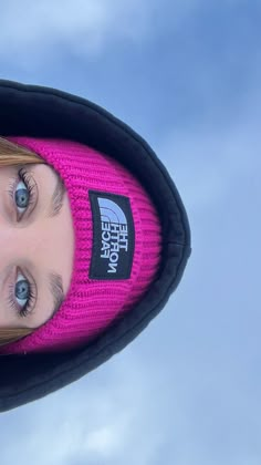 a woman wearing a pink beanie with the north face logo on it's side