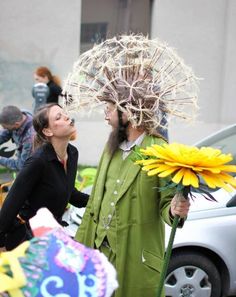 a man in a green suit with flowers on his head is standing next to a woman