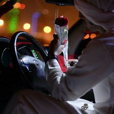 a person sitting in a car holding a flower