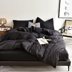 a bed with black sheets and pillows in a room