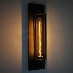 a wall light that is on the side of a white wall with a black frame