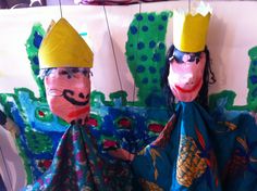 two paper mache clowns with hats and scarves on their heads, sitting next to each other