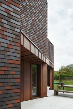 a brick building with a wooden bench in front of it and trees behind the building