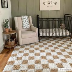 a baby's room with a crib, chair and sign on the wall