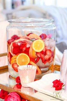 a glass jar filled with fruit and ice on top of a table next to a plate