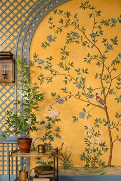 a room with a tree painted on the wall and potted plant next to it